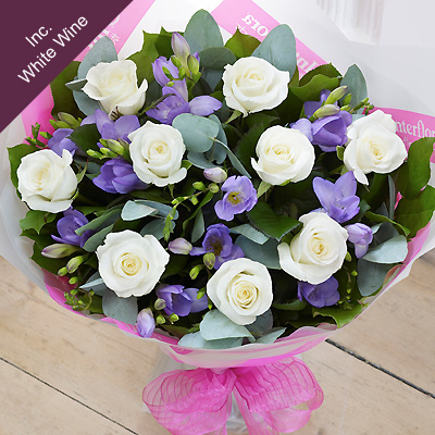 Delicate Freesia, 14 large-headed Roses and choice foliage are tied together to create this beautifu