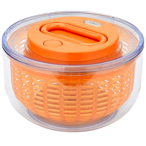 A fast-moving orange acrylic salad spinner with a transparent outer case and stop button. The