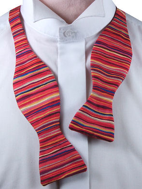 A funky self-tie bow tie with red, blue, yellow, orange and brown vertical stripes all over.