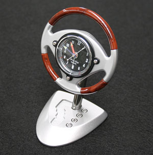 A wood rim effect steering wheel with a centre alarm clock mounted on an automatic gear shift metal 
