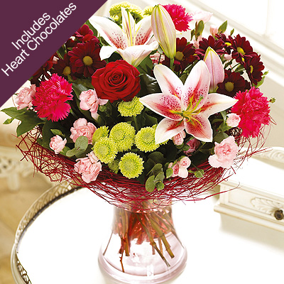 A single red Rose is nestled amongst an endearing selection of of rich red and perfectly pink flower